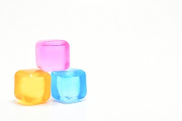 Cubos de hielo de colores sobre aislados en un fondo blanco. Espacio para texto al lado derecho.