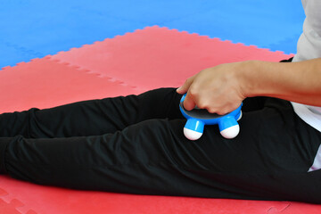 Hombre hispano usando un masajeador electrico para aliviar lesiones musculares en las piernas.