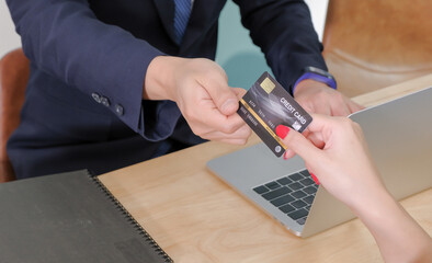 Asian middle-aged male counter service staff receiving a mock up credit card from young female...