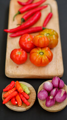 Indonesian chili sauce ingredients isolated on black background. Red chili, shallot, hillbilly tomato, red hot chili pepper.