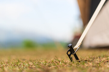 closeup black steel anchor land or pegs to hold camping tent steady on nature grass meadow to lawn...
