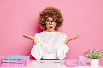 Confused office woman worker, spread hands a side in a confusion gesture, opened eyes widely in a...