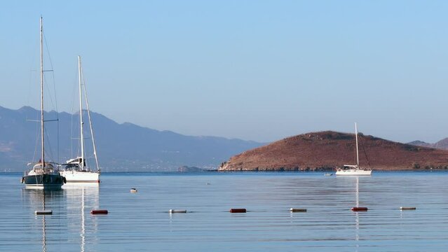 Beautiful bay with calm blue sea, sailboats, islands and mountains