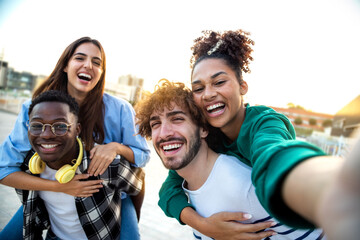 Multiracial happy friends having fun taking group selfie portrait on city street. Diverse people laugh together outdoors
