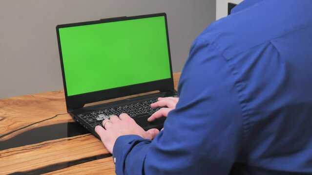 Side View Of A Man Behind A Laptop. Over Shoulder View Of White Male Businessman And Laptop With Green Screen