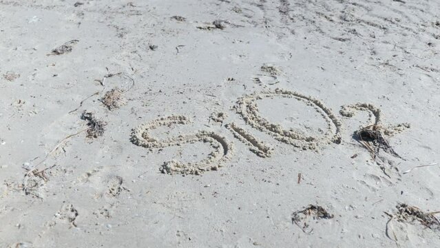 SiO2 Silicon Dioxide Silica written on beach in sand
with finger Slow Circular Pan