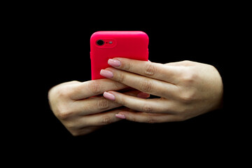 image of a female hand holding a pink mobile phone on a background of black clothes