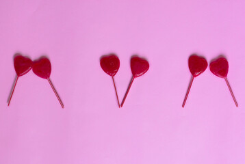 valentine background. heart shaped lollipops distributed in a line on a pink background leaving...