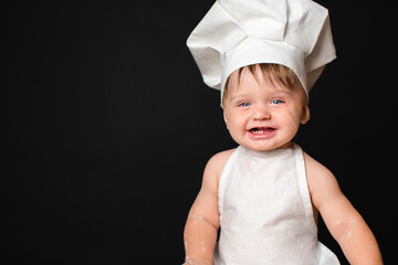 Portrait of laughing little boy in suit of the cook dirty in flour who looking at camera. Copy Space