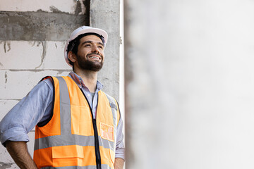 engineer handsome man or architect looking forward with white safety helmet in construction site. Standing at modern building construction. Worker asian man working project building