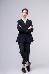 Obraz na płótnie Canvas Attractive business young woman posing in business black suit with short haircut and red lips on gray background with copy space. Caucasian girl professional worker