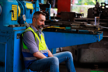 Fototapeta na wymiar Tired hot wiping sweat. Portrait hispanic latin male engineer factory manager worker and mechanic sitting in factory workplace