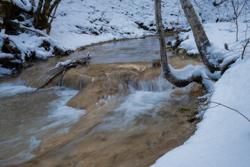 River forest winter. Winter atmospheric background. The concept of snow melting the onset of spring. The bright sun breaks through the trees. Fabulous landscape. A walk through the snow-covered forest