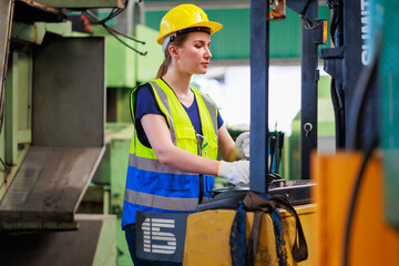 Caucasian female warehouse worker driving forklift truck at factory warehouse.