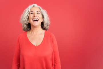 A happy mature woman laughing while standing - obrazy, fototapety, plakaty