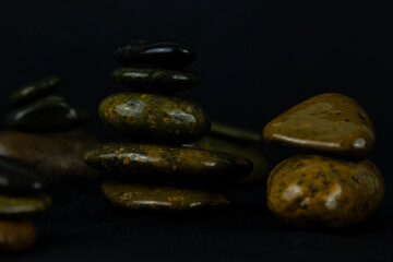 Layers of dark stones in black background used for relaxing concepts as yoga, massage and peace space stones concept of wallpaper design.
