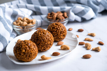 Energy bar nut balls cookie on white plate with almond and cashew. Recipe of simple homemade cookie with nuts full of protein and fats. Ketogenic diet or paleo diet dessert.