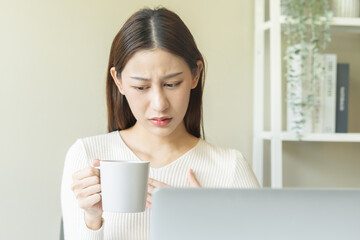 Palpitation, suffer asian young woman holding mug, drinking strong a cup of coffee, touching her...