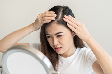 Damaged Hair symptom, face serious asian young woman, girl worry about balding, looking at scalp in...