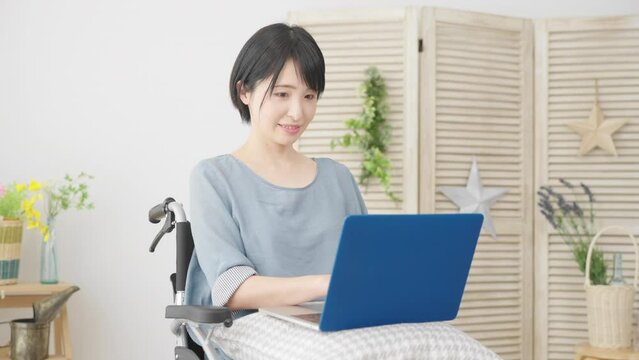 車椅子でノートパソコンを使う若い女性　多様性社会イメージ