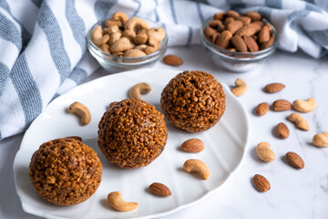 Cookie balls made of biscuit crumbs, cashew and almons nuts and caramel on white plate. Easy recipe of homemade dessert without baking. Bliss balls for tea time.