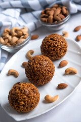 Cookie balls made of biscuit crumbs, cashew and almons nuts and caramel on white plate. Easy recipe of homemade dessert without baking. Bliss balls for tea time.