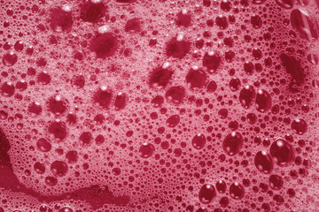 Pink foam texture. Viva magenta abstract background. The trending color of 2023. Macrophotography of shampoo soap bubbles. Layout for the design of cosmetic brochures. Tinted image Fashionable texture