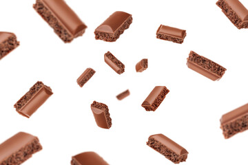 Falling porous chocolate pieces, isolated on white background, selective focus