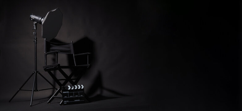 Black Director chair and clapper board and studio light on black background.