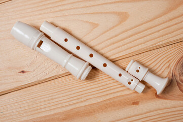 Block flute wind musical instrument photographed on a wooden surface.