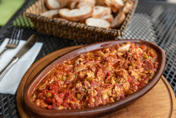 Turkish breakfast dish of Menemen with Eggs, Cheese, Tomatoes, and Peppers served with bread in a...