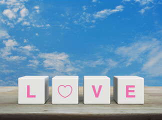 LOVE letter on white block cubes on wooden table over blue sky with white clouds, Valentines day concept