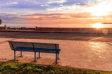 metallic bench on sea embarkment with asphalt road and beautiful seashore landscape with amazing cloudy sky