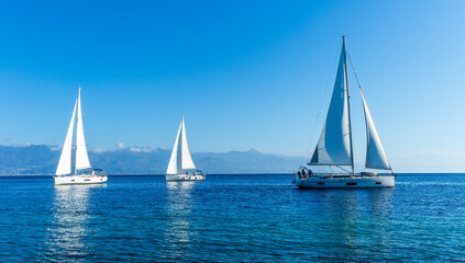 Fototapeta premium sailing yacht boats with white sails in blue sea , seascape of beautiful ships in sea gulf with mountain coast on background