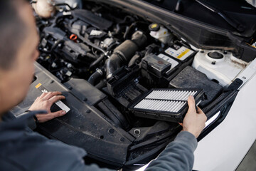 An auto mechanic changing air filters on broken car at mechanic's shop.