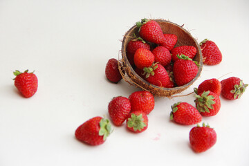 Strawberries in coconut peel. Juicy, red strawberries in a coconut plate on a white background