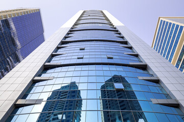 Symmetrical view of a modern skyscraper with a glass facade in Dubai, as seen from street level