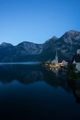 Hallstätter See in Österreich mit beleuchteter Kirche zur blauen Stunde.