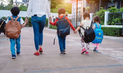 Mother and pupil and kids holding hands going to school in first class with schoolbag or satchel walking to school bus, Parent and son,sister preschool - obrazy, fototapety, plakaty