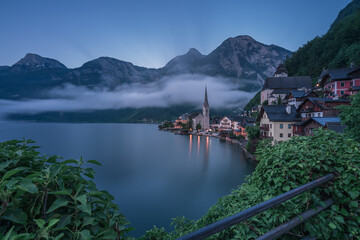 Fototapeta na wymiar Nebliger Morgen am Hallstätter See mit grünen Blättern und Lichtern.