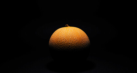 on a black background close-up half of a melon in the dark