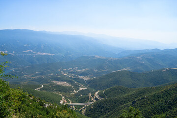 Panoramic view of top of mountains, highway bridge in sunny summer weather in Greece. Aerial view