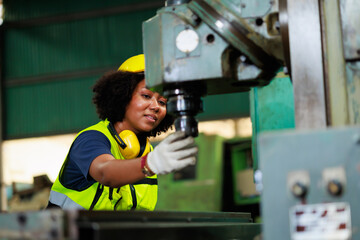 Fototapeta premium Woman worker wearing safety goggles control lathe machine to drill components. Metal lathe industrial manufacturing factory