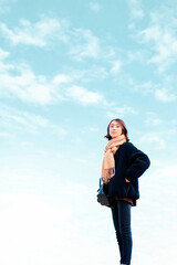 青空とベージュのマフラーを巻いた若い女性