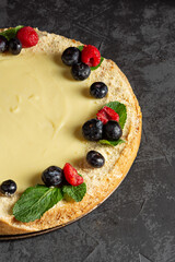 Homemade classic cheesecake on dark background. Decorating sweet cake with fresh berries
