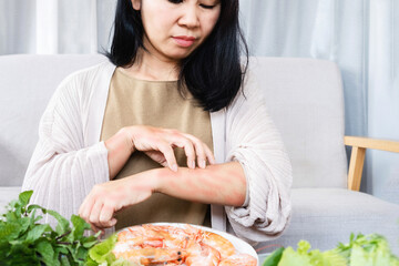 Asian woman have problems with itching rashes skin and scratching her arms caused by food allergies...
