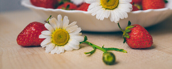 The first spring useful red berry - Strawberries in daisies on a plate close-up
