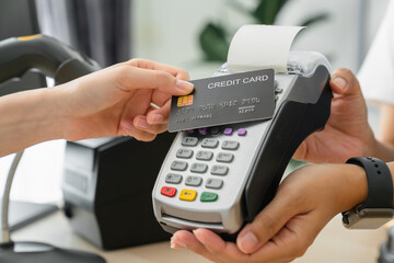 Customer using credit card for payment by NFC technology on card reader machine to owner at...