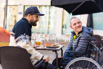 Friends eating in a restaurant terrace, disabled person, wheelchair