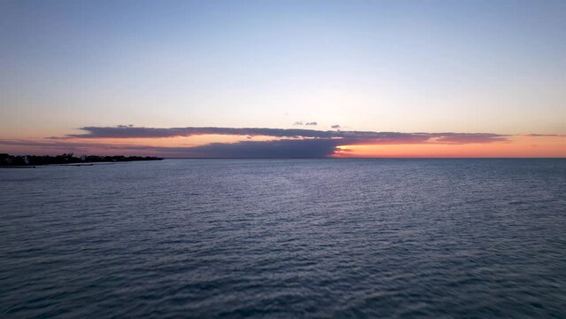 Drone capturing orange sunset, flying over ocean on Holbox Island in Mexico